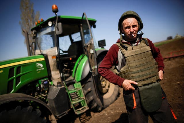 Yuri, a Ukrainian farmer, wearing body armor and helmet, works at the topsoil in a field, amid Russia's invasion of Ukraine, in Zaporizhzhia region, 乌克兰
