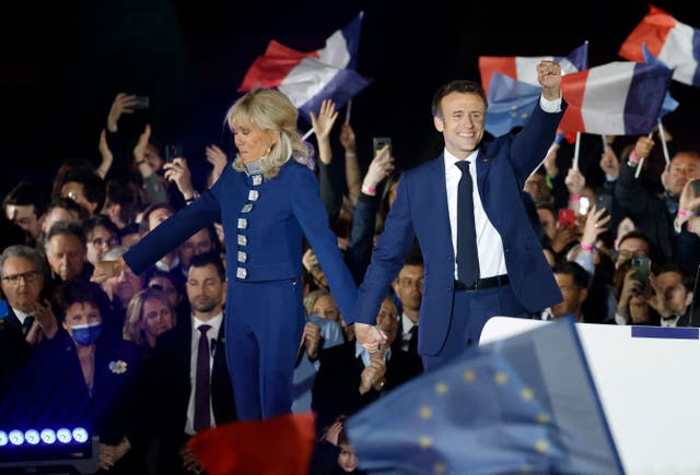 French President and La Republique en Marche (LREM) party candidate for re-election Emmanuel Macron (电阻) holds his fist in the air as he holds Brigitte Macron’s hand after his victory in France’s presidential election, at the Champ de Mars in Paris