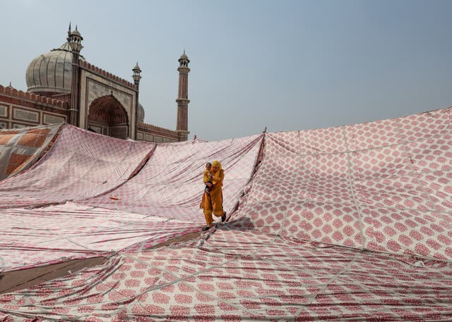 A Muslim woman with a child leaves after offering prayers during Jumat-ul-Vida or the last Friday of the holy fasting month of Ramadan, at Jama Masjid in the old quarters of Delhi, India