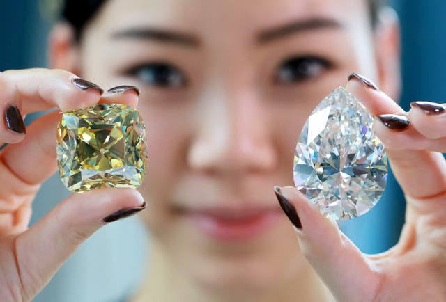 Returning for the third time since its mining in 1901, the 'Red Cross', a fancy intense yellow, cushion-shaped 205.07 carat diamond and a 228.31 carat white diamond called 'The Rock' that could fetch 30 million US dollars and is the largest ever seen throughout auction market history are pictured during a preview at Christie's before their auction sale in Geneva, Switserland
