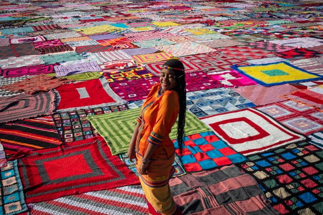 A performer stands in front of thousands of knitted blankets on the school field at Steyn City, to mark the upcoming Nelson Mandela Day, as part of the 67 Blankets for Nelson Mandela Day project in Johannesburg, Suid-Afrika