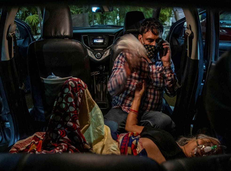 <p>Manoj Kumar waves a handkerchief from the back seat of his vehicle at his mother Vidhya Devi as she receives oxygen in the parking lot of a Gurudwara in Ghaziabad on 24 April 2021</磷>