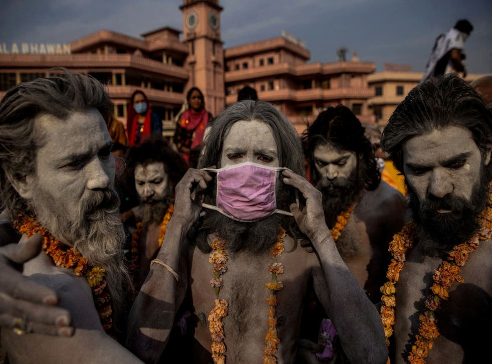 <p>A ‘Naga Sadhu’, or Hindu holy man, places a mask across his face before entering the Ganges river during the traditional Shahi Snan, or royal dip, at the Kumbh Mela festival in Haridwar on 12 April 2021</bl>