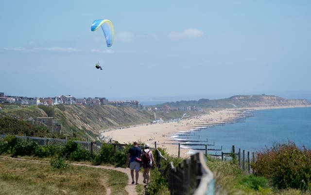 Heat haze softens the scene as a paraglider takes to the sky over the cliffs above Boscombe beach in Dorset