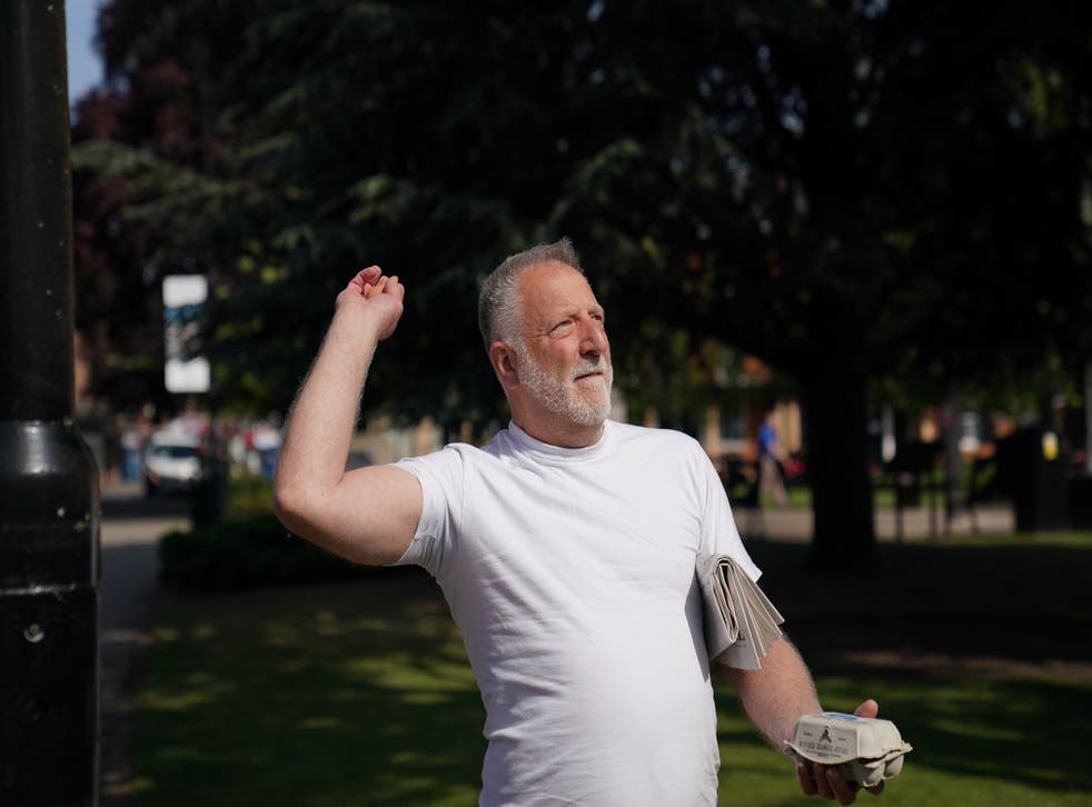 <p>A man in a white t-shirt throws eggs at a statue of Thatcher</p>