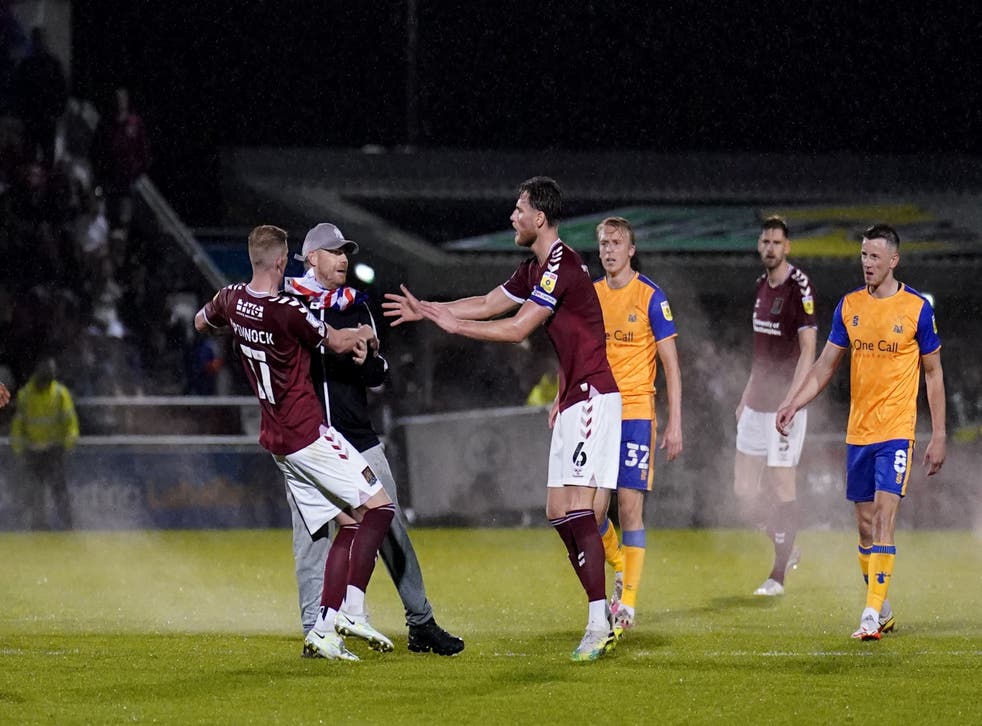 Northampton players attempt to restrain a pitch invader during the League Two play-off semi-final against Mansfield on Wednesday (Tim Goode/PA)