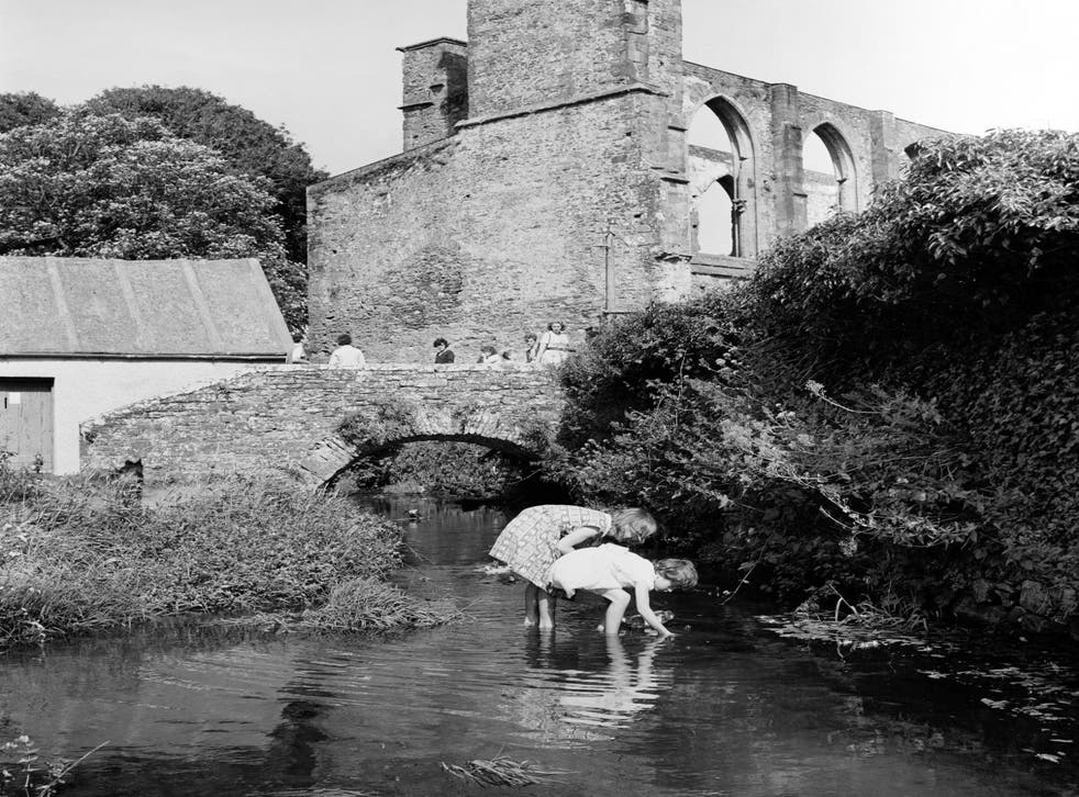 Two children paddle in a stream near the cathedral in Britain’s smallest city of St David’s, Pembrokeshire in 1962 (PA)