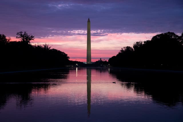 People look at the sun rising at the Lincoln Memorial Reflecting Pool in Washington, CC