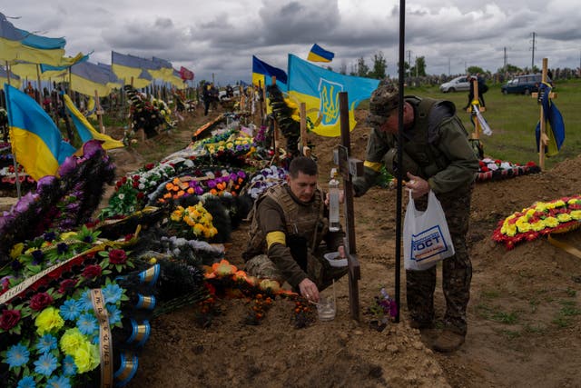 Two national guard visit the grave of a late soldier in Kharkiv cemetery, Est de l'Ukraine