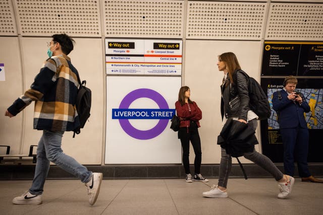 People walk past the Liverpool Street station sign along the Elizabeth Line on its first day of service as it joins the London Underground network in London, Britain