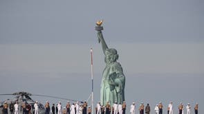 Sailors and Marines line the deck of the USS Bataan, a US Navy Wasp-class amphibious assault ship, as it sails past the Statue of Liberty among the parade of ships during “Fleet Week 2022” in New York City