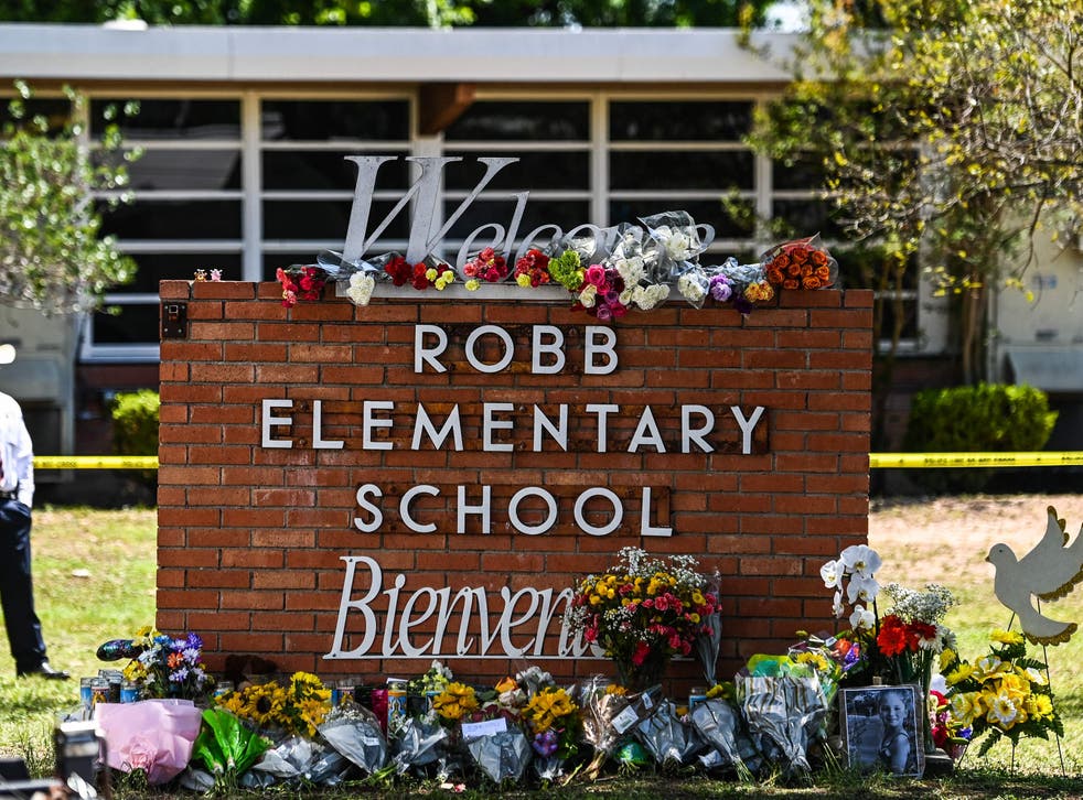 <p>Flowers are placed on a makeshift memorial in front of Robb Elementary School</磷>