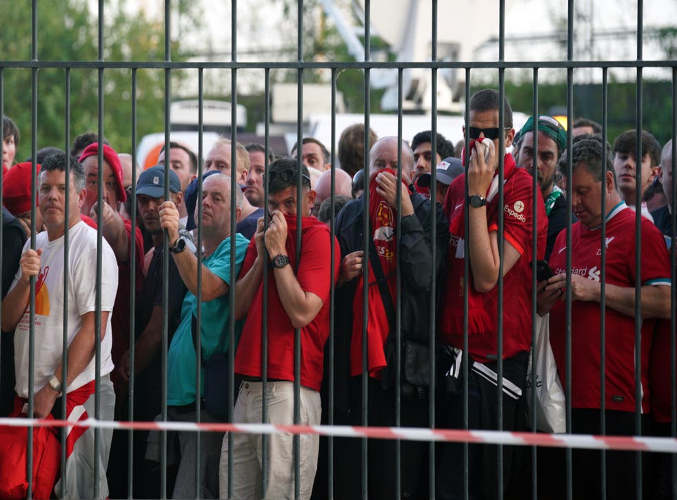 Liverpool fans cover their mouths and noses as they queue to gain entry to the stadium (Peter Byrne/PA)