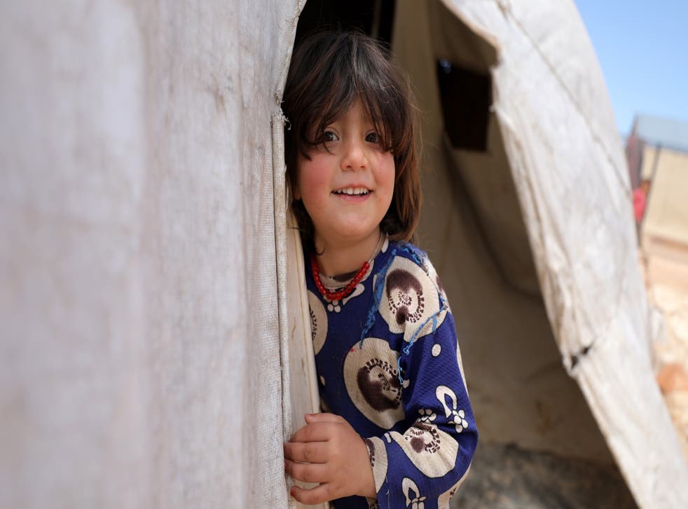 <p>A child poses for a photo from a makeshift shelter at Al-Tehh camp for Syrians in Idlib</磷>