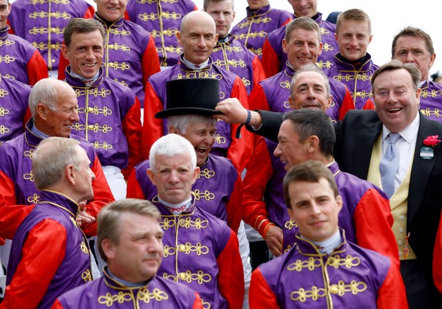 Past and present jockeys who have ridden Queen Elizabeth II’s horses line up dressed in her colours on Derby Day