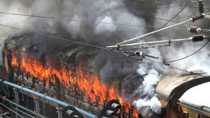Flames rise from a train set on fire by protestors at Secundrabad railroad station in Hyderabad, インド,