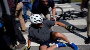 U.S. President Joe Biden falls to the ground after riding up to members of the public during a bike ride in Rehoboth Beach, デラウ�我ら��, U.S.