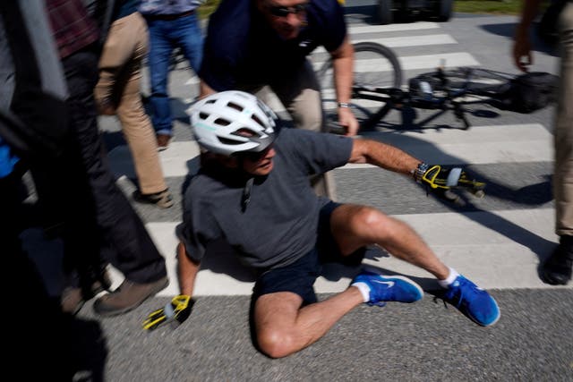 U.S. President Joe Biden falls to the ground after riding up to members of the public during a bike ride in Rehoboth Beach, 特拉华�我们 U.S.