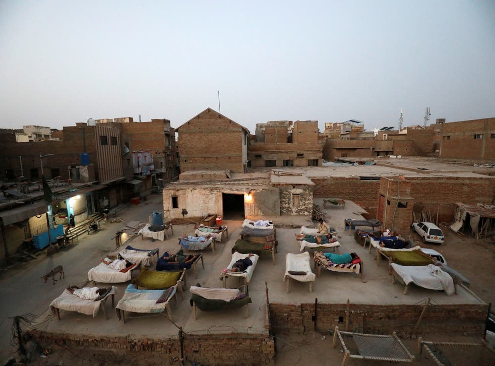 <p>Men sleep on charpoy rope beds on a roof early in the morning during a heatwave </p>