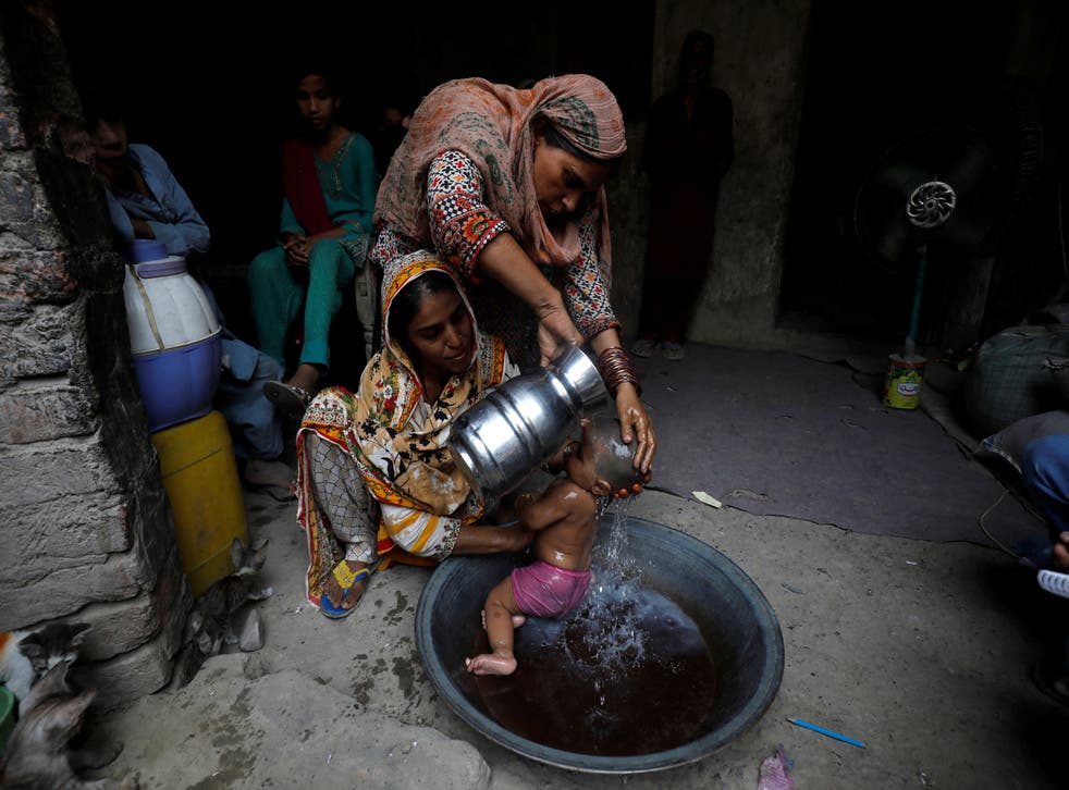<p>Rehmat, 30, helps Razia, 25, bathe her six-month-old daughter Tamanna to cool off during a heatwave</p>
