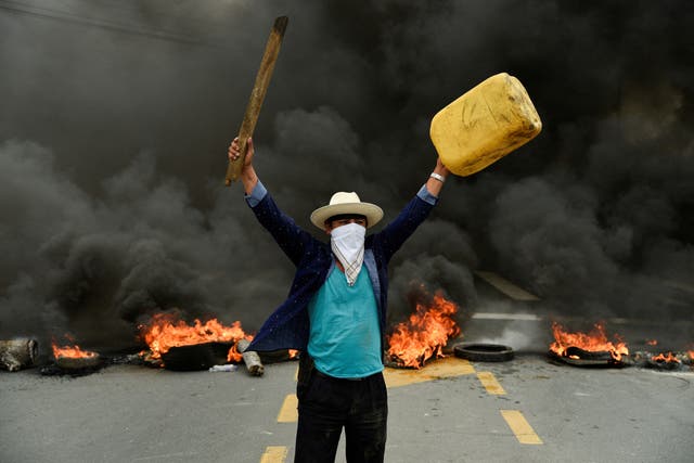 A protester gestures in front of a burning roadblock on a highway to Guayaquil during continuing demonstrations against the government of President Guillermo Lasso due to price increases for fuel, food and other basics, in Limonal, Equador