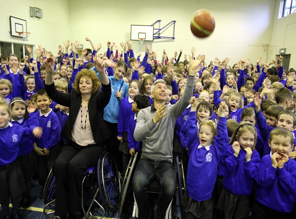 <p>Olympic gold medallist Jonathan Edwards (センター) demonstrates wheelchair basketball to pupils at St Colmans Primary School, ベル�p�ァスト </p>
