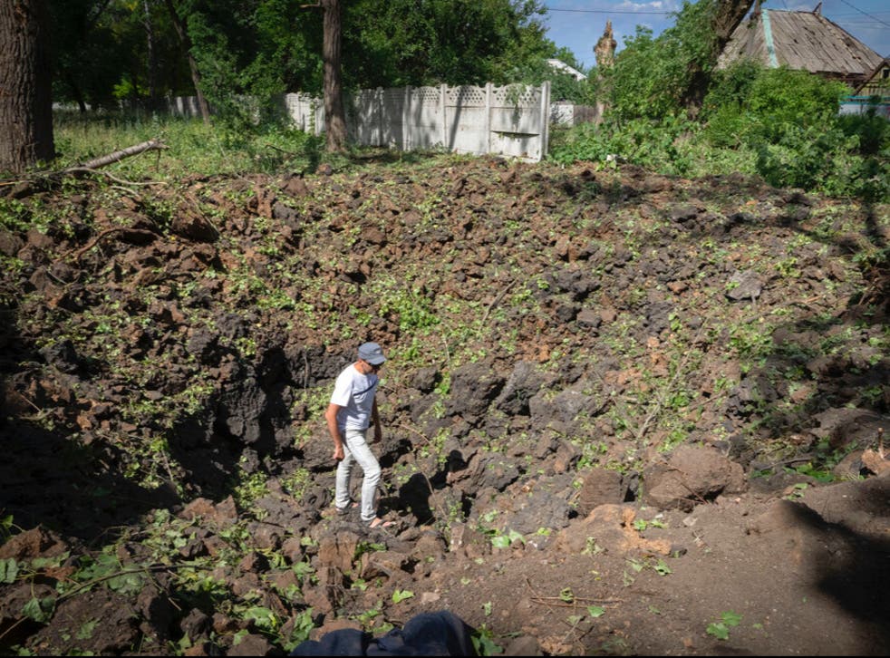 <p>A man inspects the crater left by the Russian rocket in Bakhmut, Donetsk region</s>