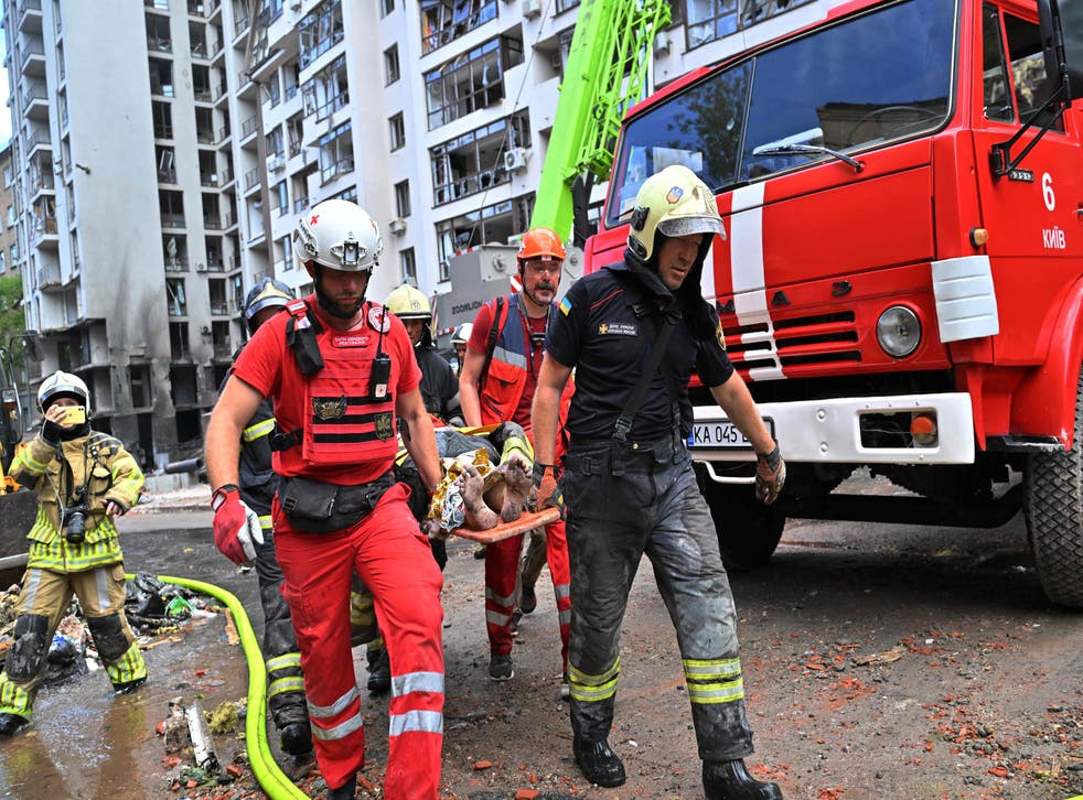 <p>Emergency workers take a woman injured in the attack to safety </p>