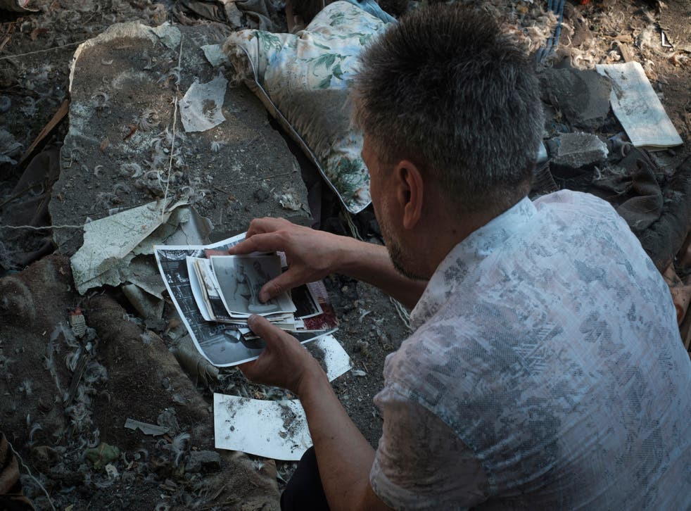A local resident collects photos of his family left under the rubble after Russian shelling in Mykolaiv, Ukraine (George Ivanchenko/AP)