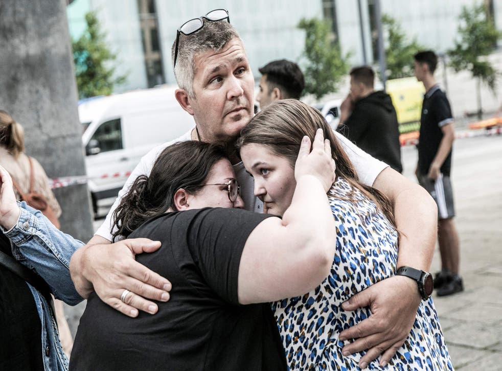 <p>People hug each other in front of the Fields shopping mall, where a gunman killed three people on Sunday </p>