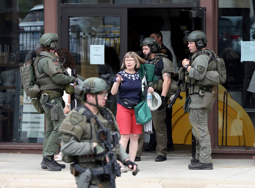 <p>Law enforcement officers help evacuate people from a store in Highland Park  </p>