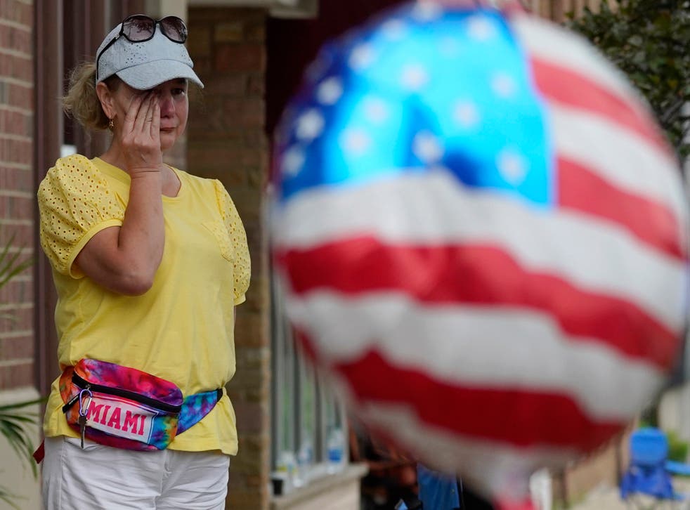 <p>Woman wipes away tears at the scene of the mass shooting </p>