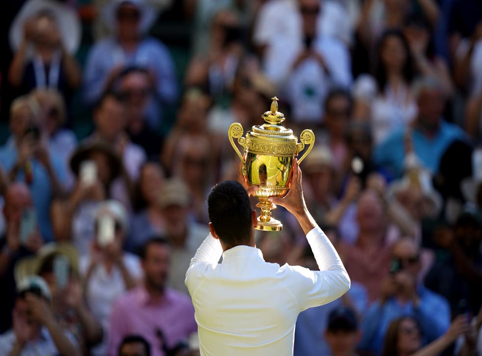 Novak Djokovic celebrates with the trophy following his victory over Nick Kyrgios (PA)