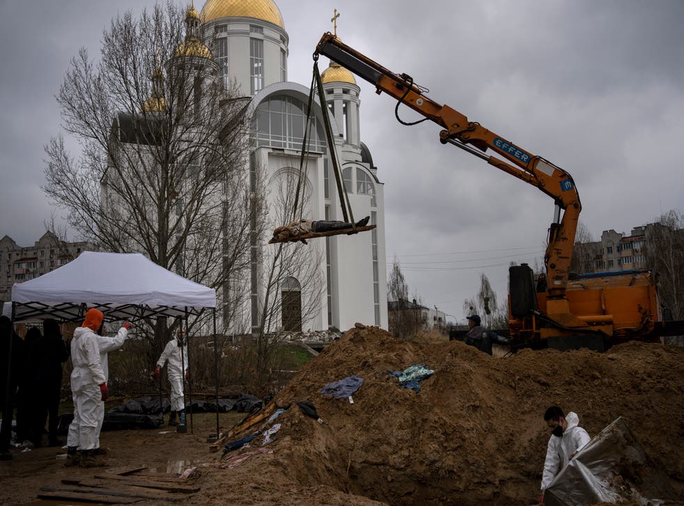 <p>A crane lifts the corpse of a man from a mass grave to be identified in a morgue in Bucha </p>