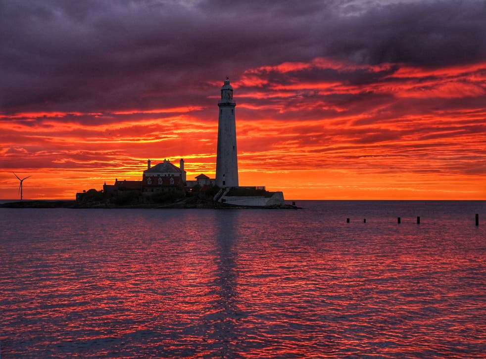 A fire coloured sky above St Mary’s Lighthouse in Whitley bay on the North East coast of England just before sunrise (Owen Humphreys/ PA)