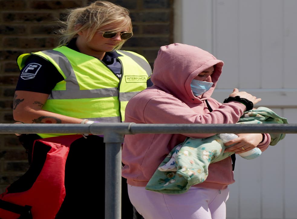A woman shields a newborn baby from the sun as migrants arrived in Kent on Monday during the heatwave (Gareth Fuller/PA)