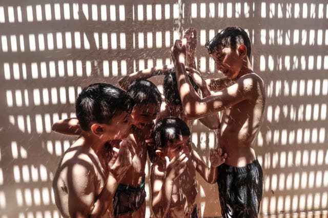 Children shower to cool off on a hot summer day in Gaza City