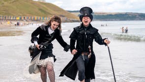 Emma Parfett and Shaun Smith paddle in the sea during the Whitby Steampunk Weekend in Yorkshire