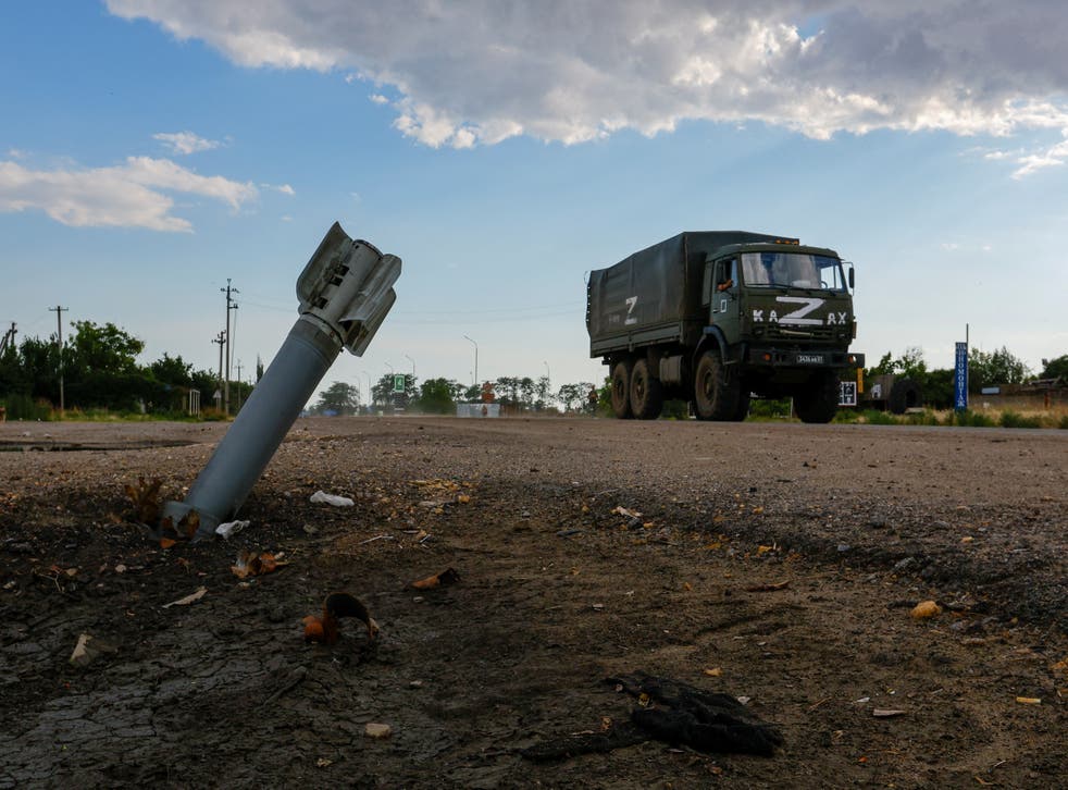 <p>A Russian military truck drives past an unexploded munition in the Russia-controlled village of Chornobaivka</p>