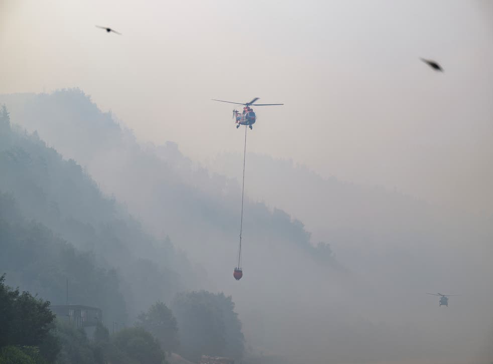 <p>A cargo helicopter from Austria takes water from the Elbe River with an external water tank to extinguish a fire</p>