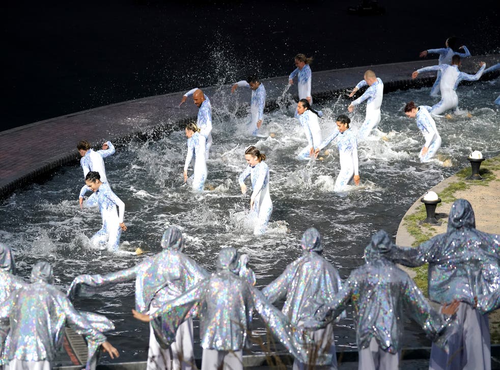Performers dance on a water-soaked stage (ザックグッドウィン/ PA)