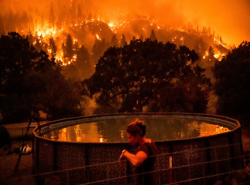<p>Angela Crawford leans against a fence as a wildfire called the McKinney fire burns a hillside above her home in Klamath National Forest, Calif., le samedi, juillet 30, 2022<pp>