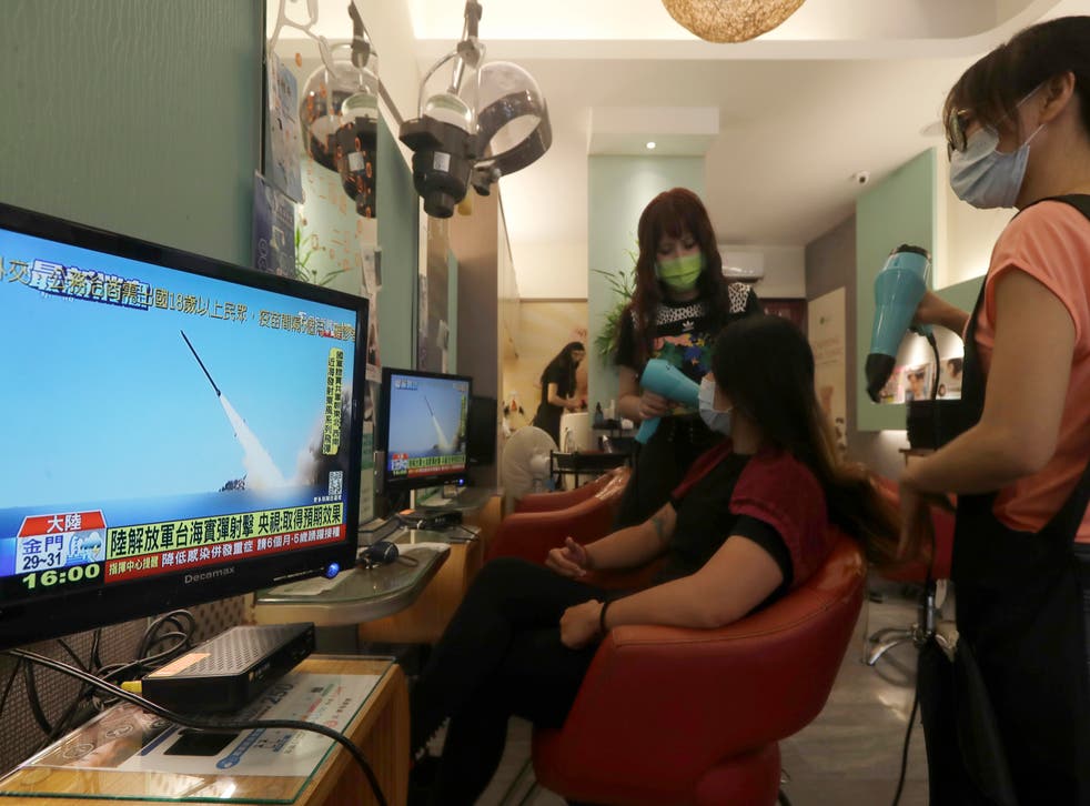 <p>A customer watches a news report on the recent tensions between China and Taiwan, at a beauty salon in Taipei</磷>