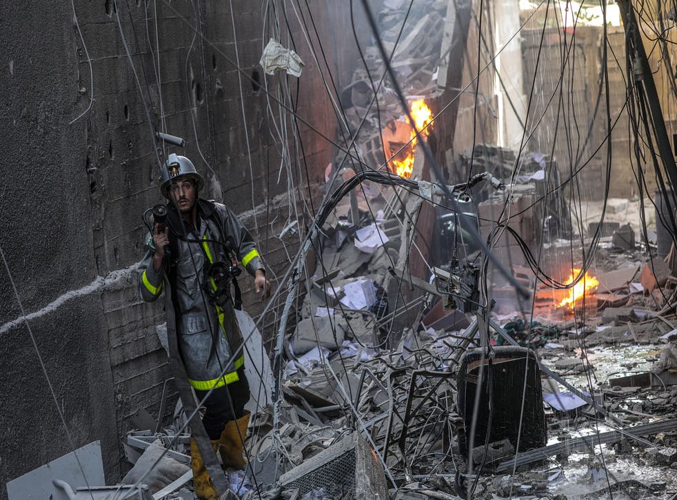 <p>A Palestinian fireman works at the site of a destroyed building</磷>