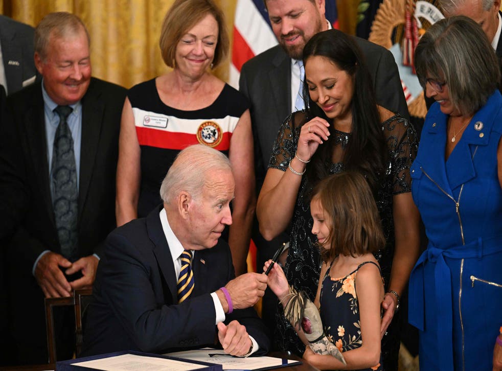<p>President Joe Biden hands a pen to Brielle Robinson, the daughter of Sgt First Class Heath Robinson, after signing the PACT Act of 2022 into law</s>
