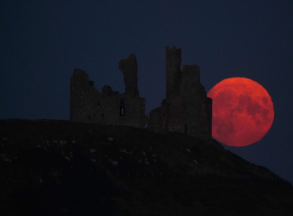 The supermoon rises over Dunstanburgh Castle in Northumberland (オーウェンハンフリーズ/ PA)