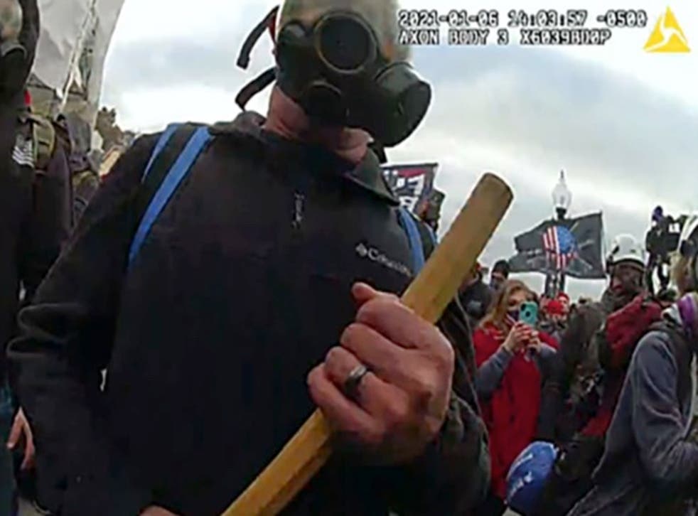 <p>Thomas Robertson wields a wooden stick to block police officers outside the US Capitol on January 6</p>