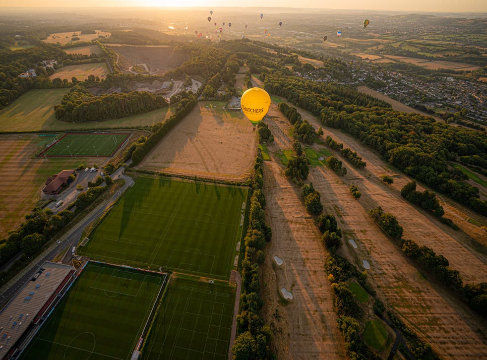 A hot air balloon flies over a browning and parched golf course (本·伯查尔/宾夕法尼亚州)