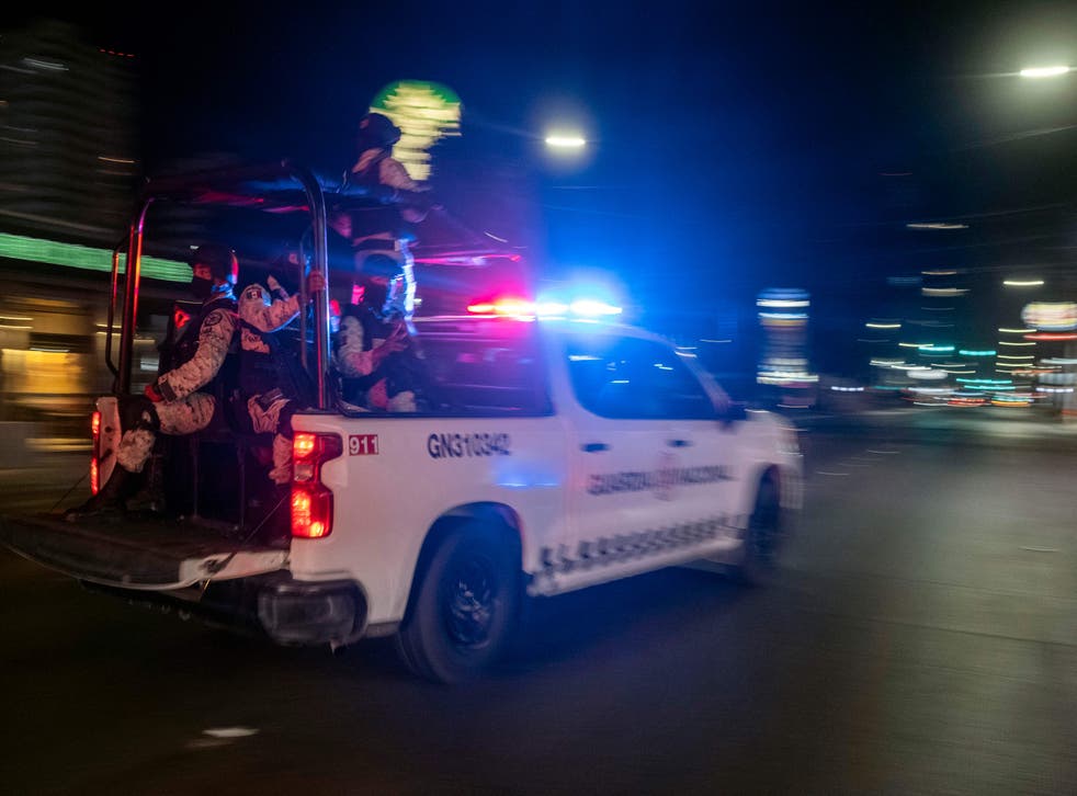 <p>Armed members of the National Guard drive past the site of a burnt collective transport vehicle after it was set on fire by unidentified individuals in Tijuana, Baja California state, Mexiko, op Augustus 12, 2022&ltbl/p>