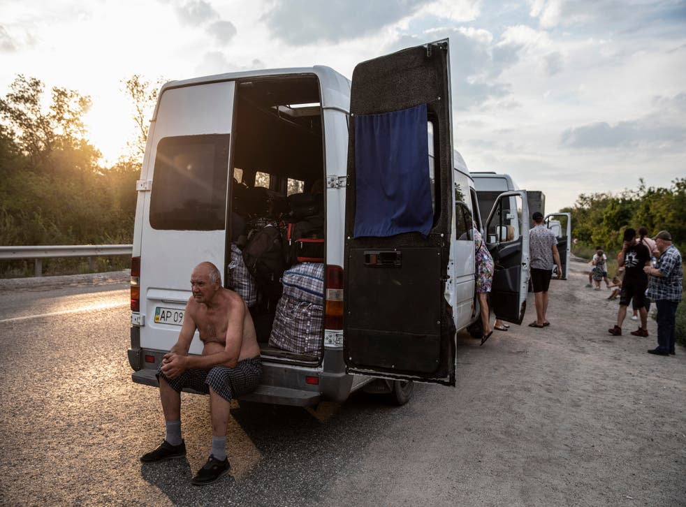 <p>Dmitri Dolghi sits at the back of a van in a convoy transporting hundreds of people fleeing Russian-controlled areas</磷>